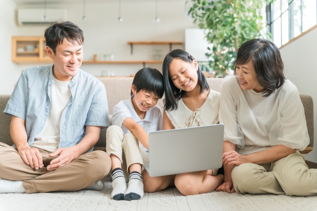 家族でノートパソコンの画面を仲良く除いている様子